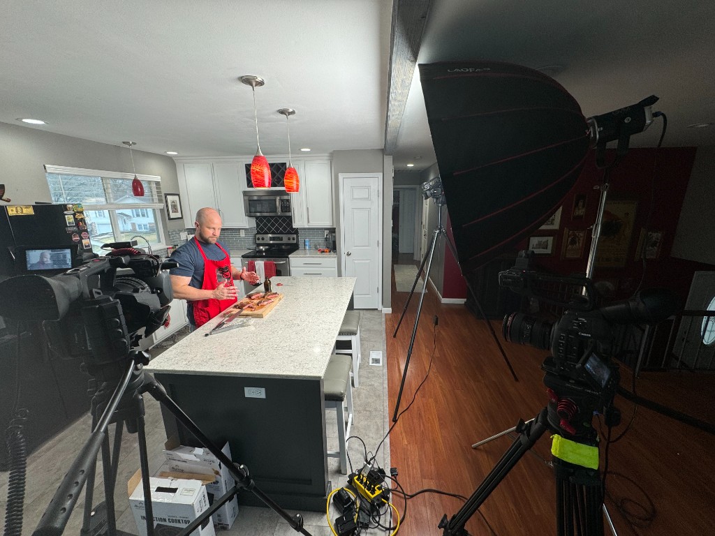 Behind the scenes of a Red Meat Lover video shoot with multiple cameras, lighting, and Joe at the kitchen island