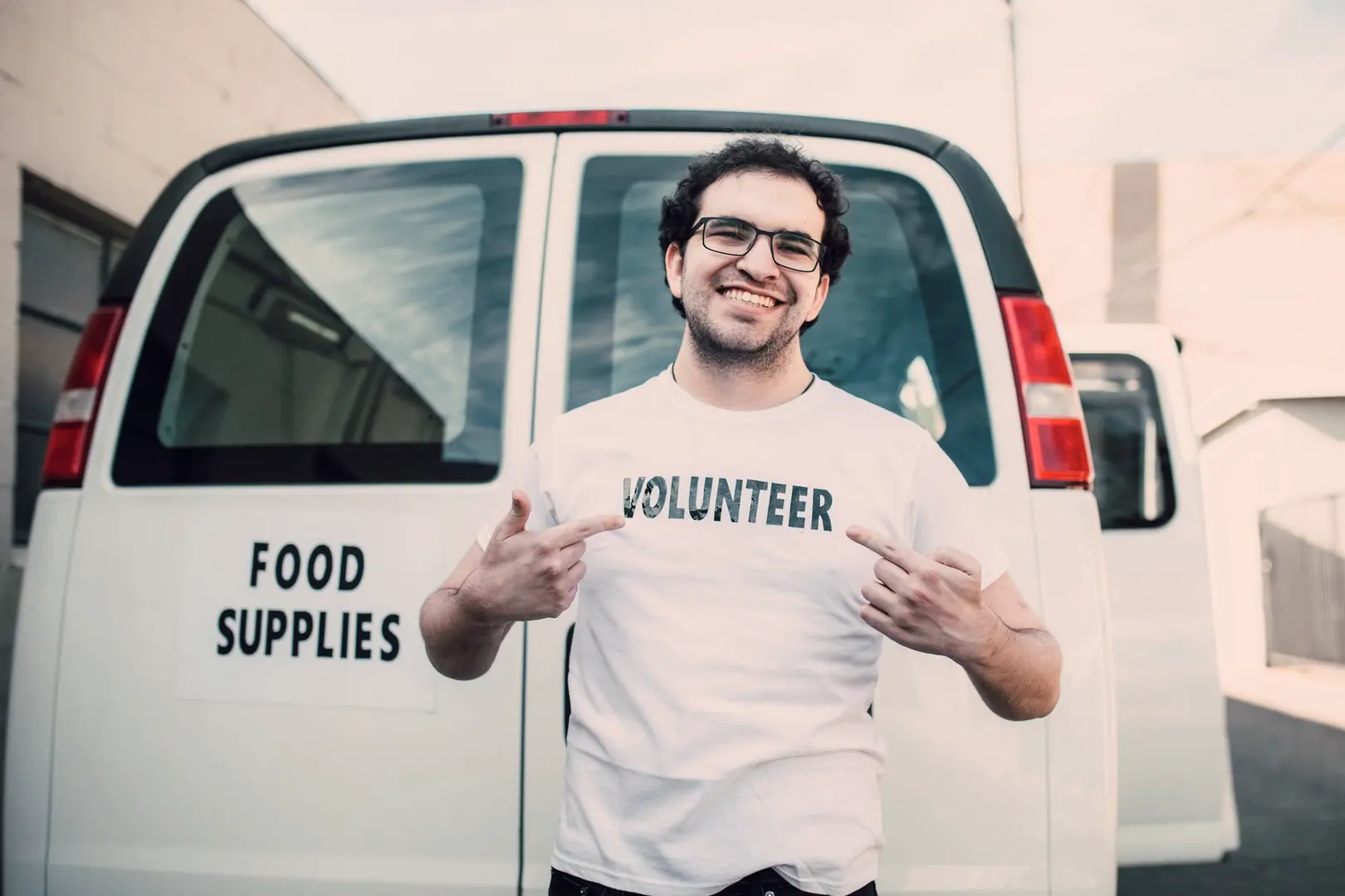 Marcus smiling and pointing at his volunteer shirt